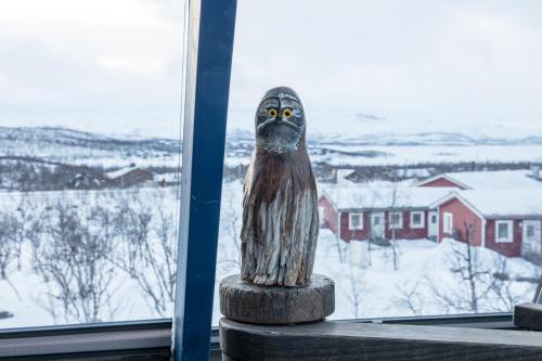 a statue of an owl sitting on a table in front of a window at Tundrea Holiday Resort in Kilpisjärvi