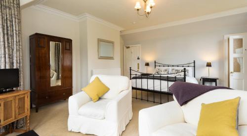 uma sala de estar com duas cadeiras brancas e uma cama em Coig na Shee Guest House em Newtonmore