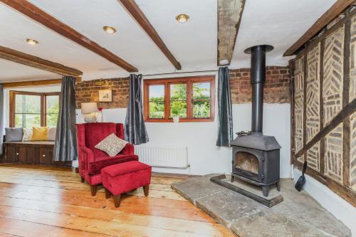 uma sala de estar com um fogão a lenha e uma cadeira vermelha em Dyke Farm Barn near Brighton by Huluki Sussex Stays em Brighton & Hove