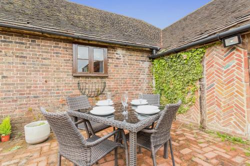 a patio with a table and chairs in front of a brick building at Dyke Farm Barn near Brighton by Huluki Sussex Stays in Brighton & Hove