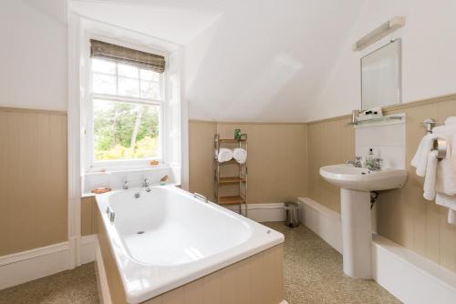 ein Badezimmer mit einer großen Badewanne und einem Waschbecken in der Unterkunft Coig na Shee Guest House in Newtonmore