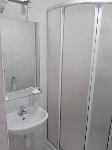 a white bathroom with a sink and a shower at Kambarių nuoma - Šiauliai SAURIDA in Šiauliai