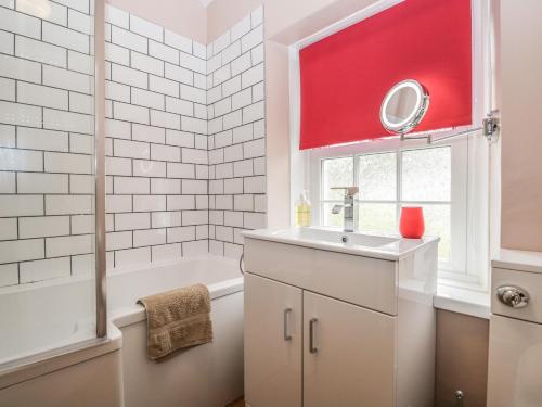 a bathroom with a sink and a tub and a red window at Mount Pleasant Cottage in Grange Over Sands