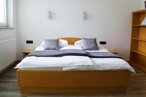 a bedroom with a bed with white sheets and blue pillows at Rudi Hiti's Guest House in Bled
