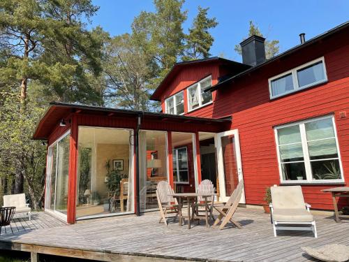 a red house with a deck with a table and chairs at Villa Myttinge in Värmdö