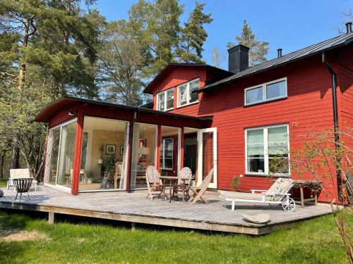 a red house with a wooden deck in front of it at Villa Myttinge in Värmdö