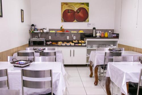 un restaurante con mesas y sillas blancas y una cocina en Gv Park Hotel, en Governador Valadares
