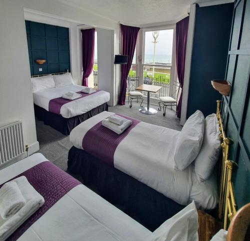 a hotel room with two beds and two windows at New Madeira Seafront Hotel in Brighton & Hove