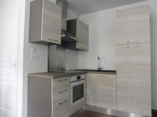 a kitchen with white cabinets and a stove top oven at Studio de charme au centre ville in Salies-de-Béarn