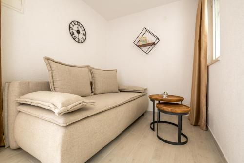 a couch with a table and a clock on the wall at Apartments Sentic in Neum