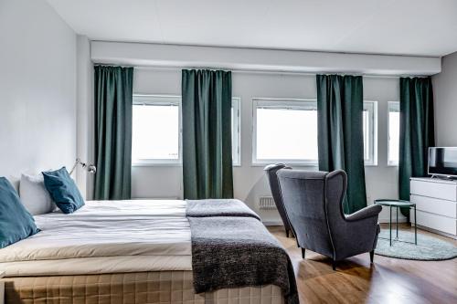 ein Schlafzimmer mit einem Bett mit grünen Vorhängen und einem Stuhl in der Unterkunft Part-Time Home Rotebro in Rotebro
