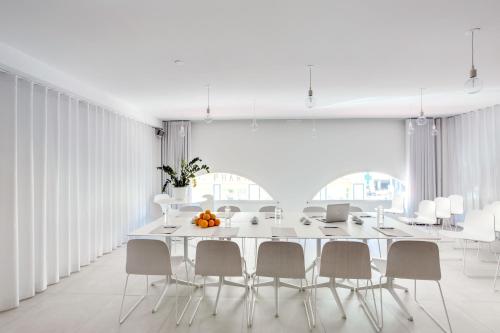 a white dining room with a large white table and chairs at Hotel du Pin Nice Port in Nice