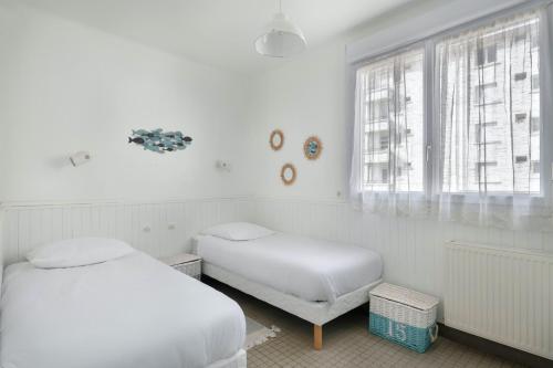 a white room with two beds and a window at Votre cocon à proximité de la plage de La Baule in La Baule