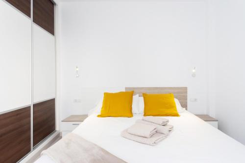 Un dormitorio con una gran cama blanca con almohadas amarillas. en Home2Book Sea Front Las Teresitas Beach 3, en San Andrés