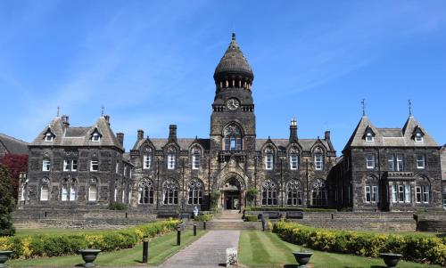 a large stone building with a clock tower at Hinsley Hall in Leeds