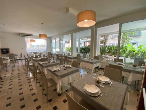 un comedor con mesas, sillas y ventanas en Hotel Lux, en Gabicce Mare