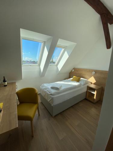 1 dormitorio con 1 cama, 1 silla y 2 ventanas en Hotel Slavia, en Boskovice