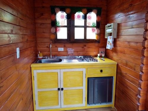 una cocina con fregadero en una cabaña de madera en La Sarita, Hospedaje rural., en Iza