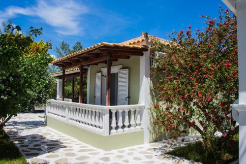 a small white house with a porch and flowers at Villas Margaris in Kalamaki