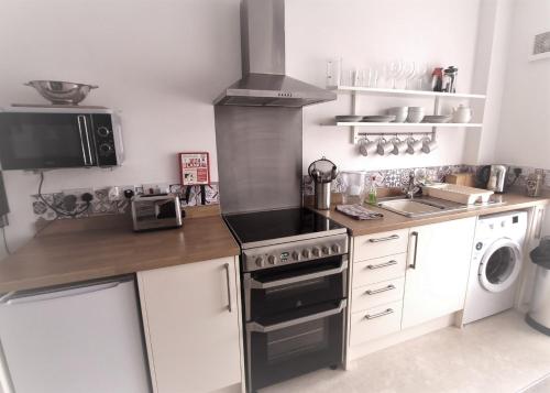 a kitchen with a stove top oven next to a dishwasher at Prince Apartments in Fareham