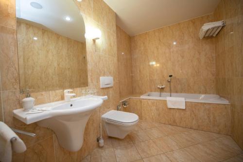 a bathroom with a sink and a toilet and a tub at ROMANTIK HOTEL ELEONORA in Tábor