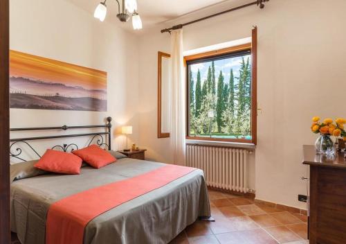 a bedroom with a bed with orange pillows and a window at Santa Margherita Vacanze in Poggibonsi