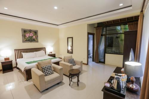 sypialnia z łóżkiem i 2 krzesłami w obiekcie Ubud Hotel & Cottages w mieście Malang