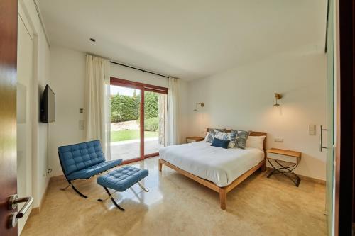 a bedroom with a bed and a blue chair at Villa Jade by Cap Vermell Estate in Canyamel
