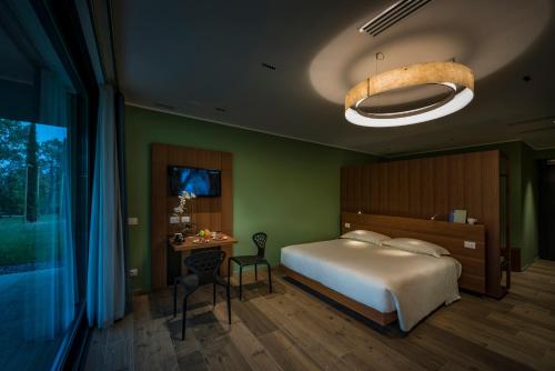 a bedroom with a bed and a table and a chandelier at Villaverde Hotel Spa&Golf Udine in Fagagna