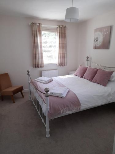 um quarto com uma cama com almofadas cor-de-rosa e uma janela em Drimvargie Mews House em Oban