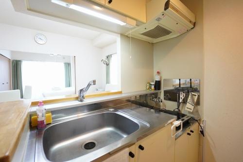 une cuisine avec un évier en acier inoxydable et une fenêtre dans l'établissement Downtown area Spacious cozy room Susukino IK1003, à Sapporo