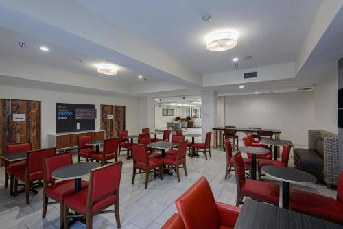 a dining room with tables and red chairs at Holiday Inn Express & Suites Corpus Christi by IHG in Corpus Christi