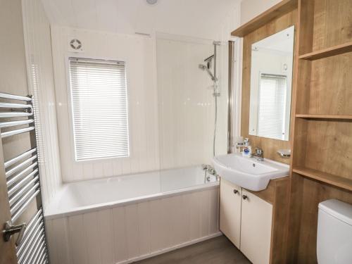 a bathroom with a tub and a sink and a mirror at Seagull Lodge in Runswick