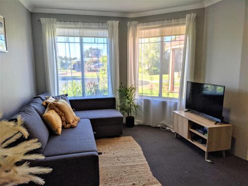 a living room with a couch and a flat screen tv at Stableford Cottage Holiday Home Dunsborough in Dunsborough
