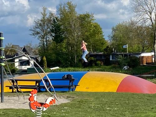 a person jumping off a slide at a playground at Vakantiehuisje Makkum NL - S15 in Makkum