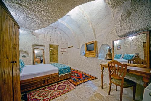 a bedroom with a bed and a desk in a room at Elysee Cave House in Goreme