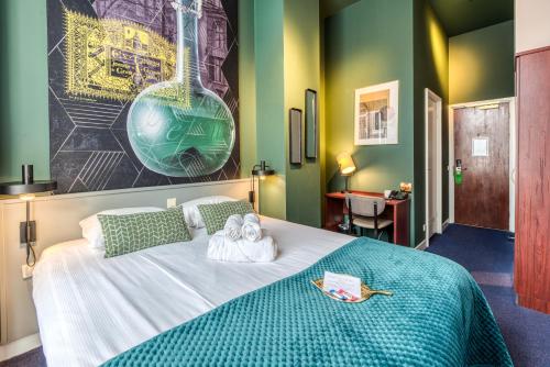 
a room with a bed, a table and a painting on the wall at Hotel Alexander in Amsterdam
