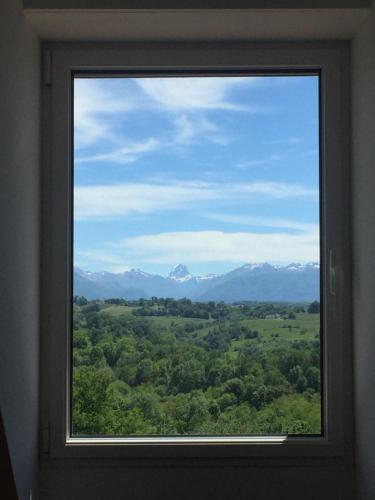 a window with a view of a field and mountains at Chambres d'Hôtes Coteaux Sud in Jurançon