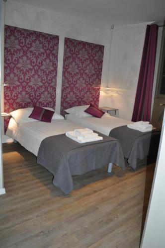 two beds in a hotel room with red wallpaper at Hôtel du Raisin in Lausanne