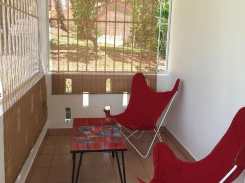 two red chairs and a table in a room at Le Belleplaine in Le Gosier