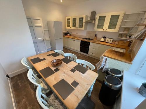 eine Küche mit einem Holztisch und weißen Schränken in der Unterkunft Kelso cobbles in Kelso