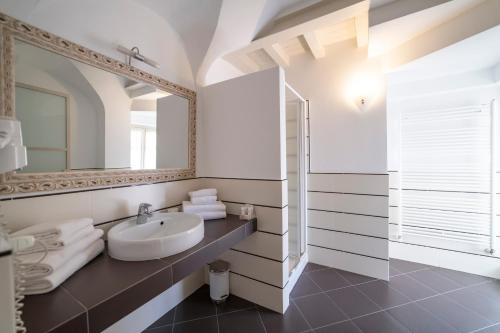 a white bathroom with a sink and a mirror at Albergo Diffuso Vulcano Village in Castro