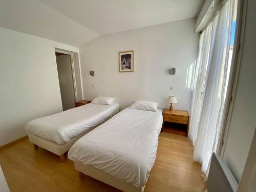 two beds in a small room with a window at Hotel Restaurant La Dame du Lac in Monflanquin