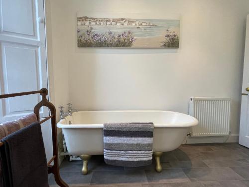 a bath tub in a bathroom with a painting on the wall at Kelso cobbles in Kelso