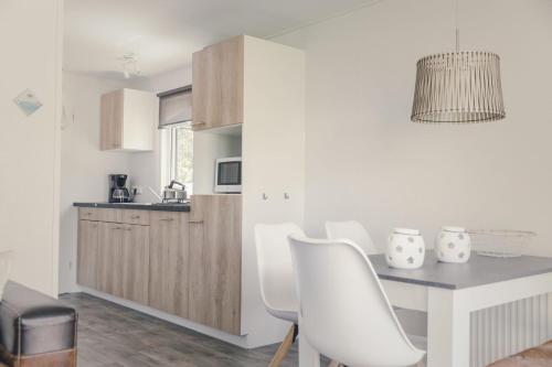 a kitchen with a dining table and white chairs at Groepsaccommodatie - 6x bungalette 5p met veranda in Zuna