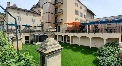 un edificio con un patio con mesas y sombrillas en Hotel-Restaurant des Augustins - Cosy Places by CC - Proche Sarlat, en Saint-Cyprien