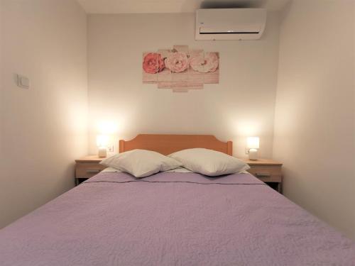 1 dormitorio con 1 cama morada y 2 almohadas en Apartmani Divić en Drvenik