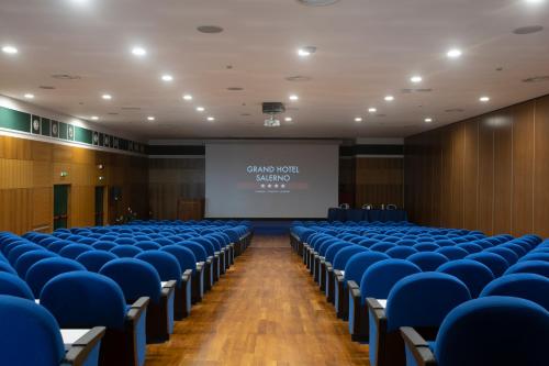 a lecture hall with blue chairs and a projection screen at Grand Hotel Salerno in Salerno