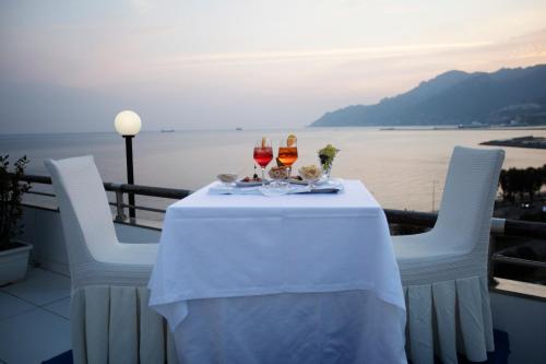 a table with two glasses of wine on a balcony at Grand Hotel Salerno in Salerno
