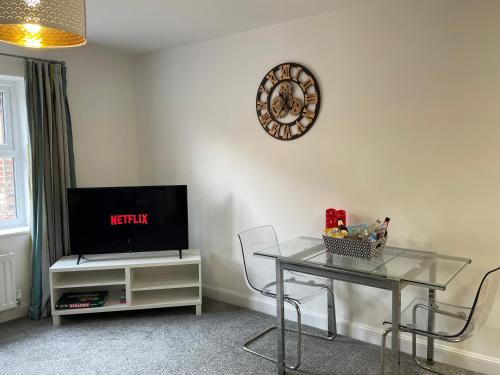 a living room with a table and a clock on the wall at Fabulous One Bedroom Apartment in Ripon City Centre in Ripon